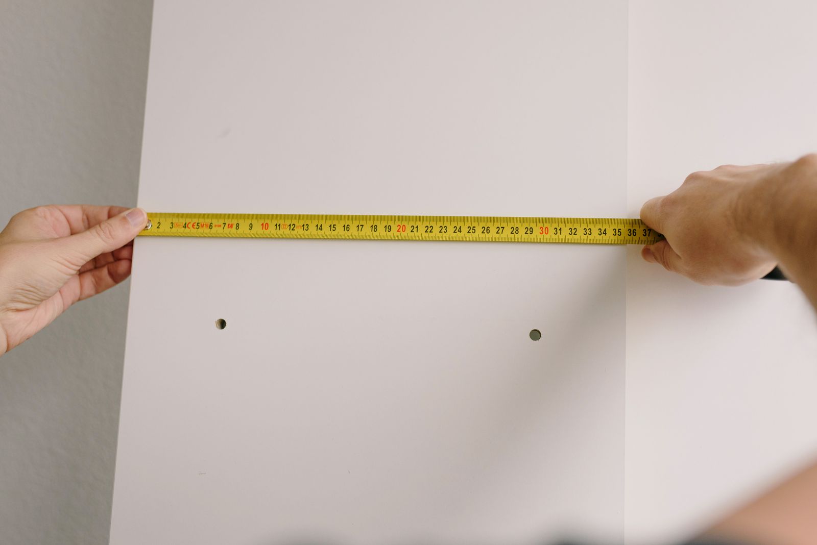 Måttband mot en vägg när butikens hyllrad mäts upp